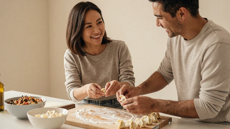 Asian woman teaching her partner to fold dumplings together during a warm kitchen date night