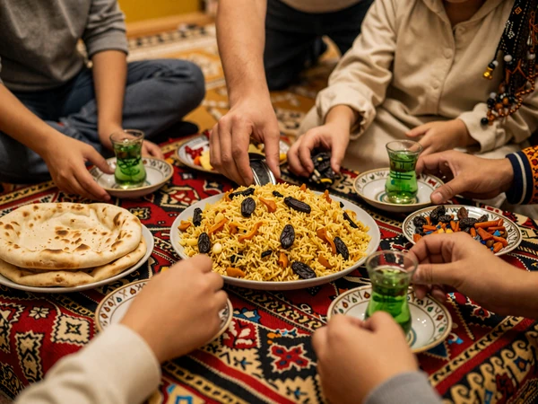 Uzbek family gathering around traditional dastarkhan sharing plov and green tea demonstrating hospitality customs